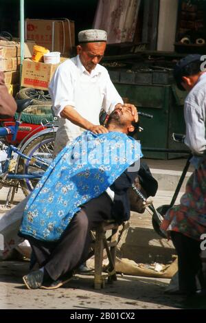 China: A shave in the sun, Kashgar, Xinjiang Province.  The earliest mention of Kashgar occurs when a Chinese Han Dynasty (206 BCE – 220 CE) envoy traveled the Northern Silk Road to explore lands to the west.  Another early mention of Kashgar is during the Former Han (also known as the Western Han Dynasty), when in 76 BCE the Chinese conquered the Xiongnu, Yutian (Khotan), Sulei (Kashgar), and a group of states in the Tarim basin almost up to the foot of the Tian Shan mountains. Stock Photo