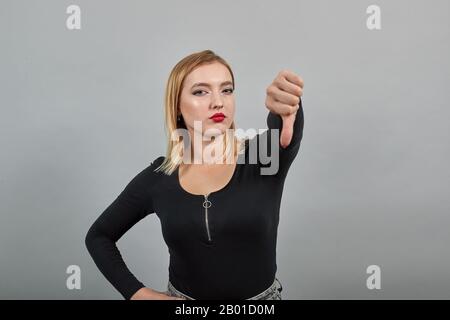 blonde girl in black jacket countering a woman who gives thumbs down, opposition Stock Photo