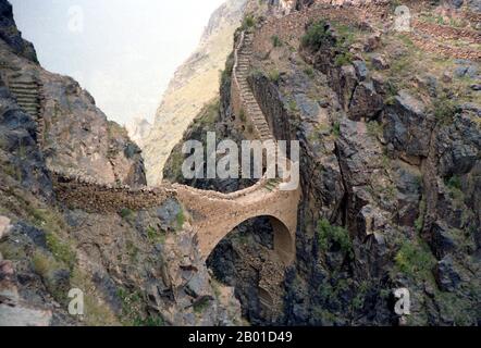 Yemen: Footbridge across a 300 metre (985 ft) chasm at Shahara, north of Sana'a. Photo by Bernard Gagnon (CC BY-SA 3.0 License), 1986.  The celebrated Shahara Bridge in Yemen was built across a 300-metre deep gorge in 1620, ostensibly to repel Turkish invasions. Shaharah is a fortified village high in the Yemeni Sarawat Mountains about six hours drive north of Sana'a.  Fortified mountain villages are common in Yemen, but Shaharah is the most inaccessible. Incredibly inaccessible, Shaharah has been a thorn in the side of any invading army and a bolthole for retreating imams for centuries. Stock Photo