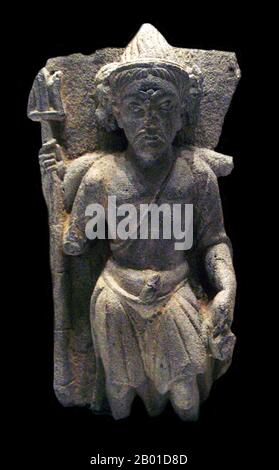 Pakistan/Afghanistan: Shiva with trident, Gandhara, 2nd century CE. Photo by PHGCOM (CC BY-SA 3.0 License).  Gandhāra is noted for the distinctive Gandhāra style of Buddhist art, which developed out of a merger of Greek, Syrian, Persian, and Indian artistic influence. This development began during the Parthian Period (50 BCE - 75 CE). Gandhāran style flourished and achieved its peak during the Kushan period, from the 1st to the 5th century. It declined and suffered destruction after invasion of the White Huns in the 5th century.  Stucco as well as stone was widely used by sculptors in Gandhara Stock Photo
