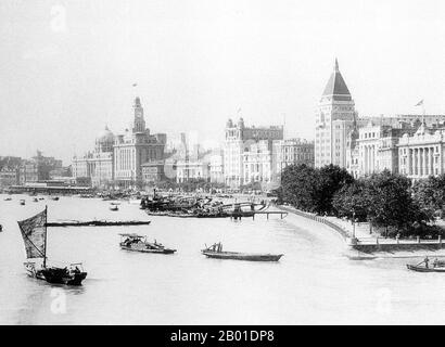 China: A view of the Bund across the Huangpu River in Shanghai, 1929.  The Bund (Chinese: Wàitān) is an area of Huangpu District in central Shanghai. The area centres on a section of Zhongshan Road (East-1 Zhongshan Road) within the former Shanghai International Settlement, which runs along the western bank of the Huangpu River, facing Pudong, in the eastern part of Huangpu District.  The Bund usually refers to the buildings and wharves on this section of the road, as well as some adjacent areas. Stock Photo