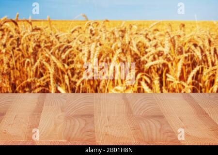 Empty wooden table with blurred wheat field on the background. Stock Photo