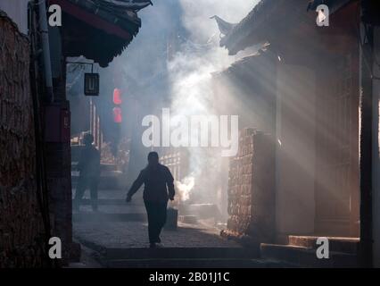 China: A smoky back street, Lijiang Old Town, Yunnan Province.  The Naxi or Nakhi are an ethnic group inhabiting the foothills of the Himalayas in the northwestern part of Yunnan Province, as well as the southwestern part of Sichuan Province in China. The Naxi are thought to have come originally from Tibet and, until recently, maintained overland trading links with Lhasa and India.  The Naxi form one of the 56 ethnic groups officially recognised by the People's Republic of China. The Naxi are traditionally followers of the Dongba religion. Stock Photo