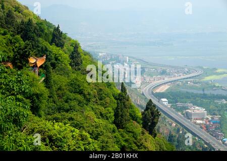 China: Highway leading to Kunming seen from Long Men (Dragon Gate), Xishan (Western Hills), near Kunming, Yunnan Province  Lying 15 km west of Kunming City, the Dragon Gate (Long Men) in the Western Hills is close to the west shore of Dianchi Lake. It consists of the Sanqing Temple Complex and the Dragon Gate Grotto Complex.  Dragon Gate is over 2,300 metres, 300 metres higher than the water surface of Dianchi Lake.  Western Hills Forest Reserve lies in the Biji Mountain chain to the west of Kunming, China. It is visible from the eastern or northern banks of Dianchi Lake. Stock Photo