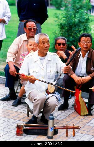 China: A man plays a banhu in a park in Wuwei, Gansu Province.  The city of Wuwei has a population of around 500,000, mainly Han Chinese, but with visible numbers of Hui as well as Mongols and Tibetans. In earlier times it was called Liangzhou. Dominating the eastern end of the Hexi Corridor, it has long played a significant role on this major trade route.  Wuwei’s most famous historic artefact, the celebrated Han Dynasty (206 BCE - 220 CE) bronze horse known as the Flying Horse of Gansu, was discovered here in a tomb beneath Leitai Temple (Leitai Si) in the north part of town. Stock Photo