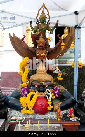 Thailand: Krut Pha (top), a garuda carrying the Hindu god Vishnu, and Rahu (Snake Demon and causer of solar and lunar eclipses), swallowing the moon, Wat Traimit, Bangkok. The National Emblem (National Symbol) of Thailand features the Garuda, a figure from both Buddhist and Hindu mythology. In Thailand, this figure is used as a symbol of the royal family and authority. This version of the figure is referred to as Krut Pha, meaning 'garuḍa acting as the vehicle (of Vishnu).'  In Hindu mythology, Rahu is a snake that swallows the sun or the moon causing eclipses. Stock Photo