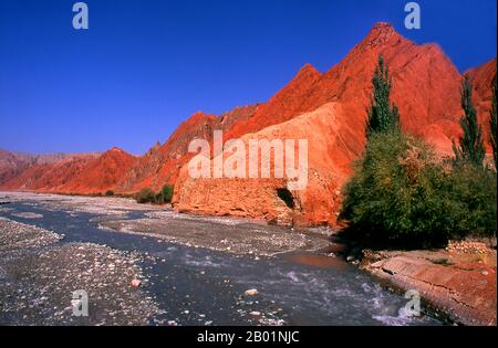 China: The red mountains of the Ghez River (Ghez Darya) canyon, Karakoram Highway, Xinjiang.  The Zhongba Gonglu or Karakoram Highway is an engineering marvel that was opened in 1986 and remains the highest paved road in the world. It connects China and Pakistan across the Karakoram mountain range, through the Khunjerab Pass, at an altitude of 4,693 m/15,397 ft. Stock Photo