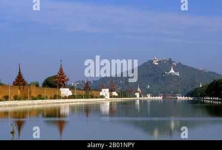 Burma/Myanmar: The moat surrounding Mandalay Fort, Mandalay Hill in the background, Mandalay.  Mandalay, a sprawling city of more than 1 million people, was founded in 1857 by King Mindon to coincide with an ancient Buddhist prophecy. It was believed that Gautama Buddha visited the sacred mount of Mandalay Hill with his disciple Ananda, and proclaimed that on the 2,400th anniversary of his death, a metropolis of Buddhist teaching would be founded at the foot of the hill. Stock Photo