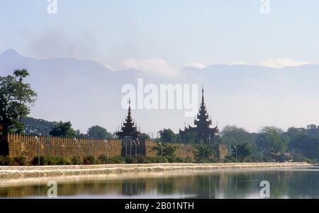 Burma/Myanmar: Early morning smoke and haze over Mandalay Fort with the Shan Plateau visible in the background.  Mandalay, a sprawling city of more than 1 million people, was founded in 1857 by King Mindon to coincide with an ancient Buddhist prophecy. It was believed that Gautama Buddha visited the sacred mount of Mandalay Hill with his disciple Ananda, and proclaimed that on the 2,400th anniversary of his death, a metropolis of Buddhist teaching would be founded at the foot of the hill. Stock Photo