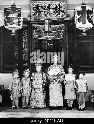 Malaysia/Singapore: A Penang bride and groom pose for their wedding photograph outside the family shophouse, early 20th century.  Peranakan Chinese and Baba-Nyonya are terms used for the descendants of late 15th and 16th-century Chinese immigrants to the Malay-Indonesian archipelago of Nusantara during the Colonial era.  Members of this community in Malaysia identify themselves as 'Nyonya-Baba' or 'Baba-Nyonya'. Nyonya is the term for the females and Baba for males. It applies especially to the ethnic Chinese populations of the British Straits Settlements of Malaya. Stock Photo