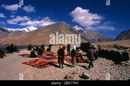 China: Kirghiz carpet traders, Karakoram Highway, Xinjiang.  Two small settlements of Kirghiz (Kyrgyz or Kirgiz) nomads lie by the side of Lake Karakul high up in the Pamir Mountains. Visitors can stay overnight in one of their mobile homes or yurts – Kirghiz men will approach travellers as they arrive at the lake and offer to arrange this accommodation. The Kyrgyz form one of the 56 ethnic groups officially recognized by the People's Republic of China. There are more than 145,000 Kyrgyz in China.  The Zhongba Gonglu or Karakoram Highway is an engineering marvel that was opened in 1986 and rem Stock Photo