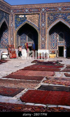 Uzbekistan: Carpets in the courtyard of the Tillya Kari Madrassa, The Registan, Samarkand.  The Registan contains three madrasahs (schools), the Ulugh Beg Madrasah (1417-1420), Tilya-Kori Madrasah (1646-1660) and the Sher-Dor Madrasah (1619-1636).  The Tilya-Kori Madrasah was built in the mid-17th century by the Shaybanid Amir Yalangtush. The name Tilya-Kori means ‘gilded’ or ‘gold-covered’, and the entire building is lavishly decorated with elaborate geometrical arabesques and sura from the Qur’an both outside and especially within. Stock Photo