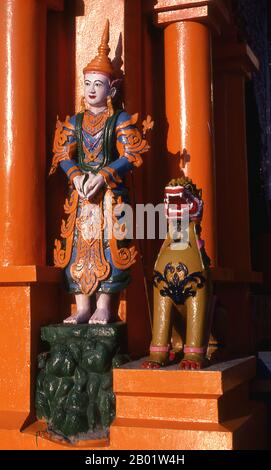 Burma/Myanmar: Figures at the door of the Temple of the Konagamana Buddha, Shwedagon Pagoda, Yangon (Rangoon).  The golden stupa of the Shwedagon Pagoda rises almost 100 m (330ft) above its setting on Singuttara Hill and is plated with 8,688 solid-gold slabs. This central stupa is surrounded by more than 100 other buildings, including smaller stupas and pavilions.  The pagoda was already well established when Bagan dominated Burma in the 11th century. Queen Shinsawbu, who ruled in the 15th century, is believed to have given the pagoda its present shape. Stock Photo