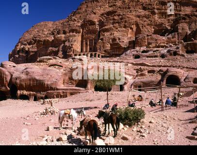 Jordan: Arab horsemen in front of the Urn Tomb, Petra.  Petra was first established as a city by the Nabataean Arabs in the 4th century BCE, and owed its birth and prosperity to the fact that it was the only place with clear and abundant water between the Hijaz trading centres of Mecca and Medina, and Palestine.  Hewn directly into the Nubian sandstone ridges of the south Jordanian desert, it seems probable that - given its excellent defensive position and good water supplies - Petra has been continually occupied from as early as Paleolithic times. It is thought to be mentioned in the Bible. Stock Photo