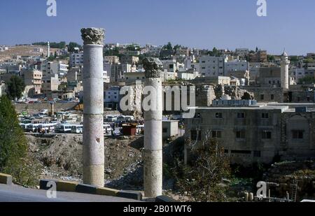 Jordan: Roman columns in front of the modern town of Jerash.  Jerash is the site of the ruins of the Greco-Roman city of Gerasa, also referred to as Antioch on the Golden River. Jerash is considered one of the most important and best preserved Roman cities in the Near East. It was a city of the Decapolis.  Recent excavations show that Jerash was already inhabited during the Bronze Age (3200-1200 BCE). After the Roman conquest in 63 BCE, Jerash and the land surrounding it were annexed by the Roman province of Syria, and later joined the Decapolis cities. Stock Photo