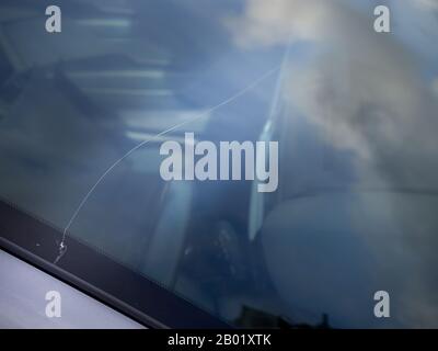 Single line of crack in car windscreen glass, cracked from the outside. Stock Photo