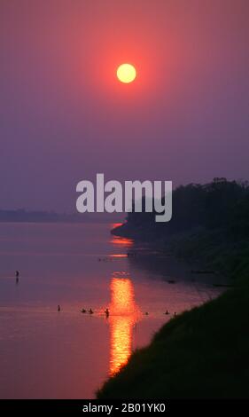 Laos: Swimmers in the Mekong River at sunset, Vientiane.  The River Mekong is the world's 12th-longest river. From its Himalayan source on the Tibetan plateau, it flows some 4,350 km (2,703 miles) through China's Yunnan province, Burma, Laos, Thailand, Cambodia and Vietnam, finally draining in the South China Sea.  The recent construction of hydroelectric dams on the river and its tributaries has reduced the water flow dramatically during the dry season in Southeast Asia. Stock Photo