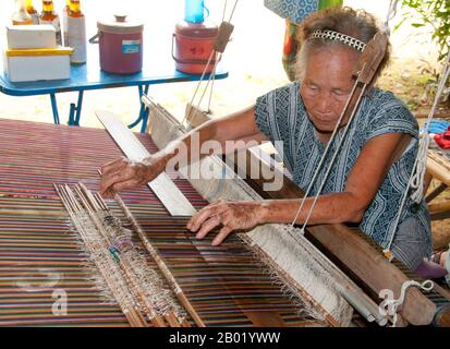 Thailand: Weavers in the Wiangyong district creating the famous Pha Mai Yok Dok silk fabrics, Lamphun, northern Thailand.  Pha Mai Yok Dok is an elaborately woven material in traditional method. Originally used in the northern royal court, it became popular during the reign of King Rama VI. The distinctive craftsmanship and skills in producing this type of silk have endeared it to those who prefer the traditional designs.  Lamphun was the capital of the small but culturally rich Mon Kingdom of Haripunchai from about 750 CE to the time of its conquest by King Mangrai (the founder of Chiang Mai) Stock Photo