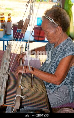 Thailand: Weavers in the Wiangyong district creating the famous Pha Mai Yok Dok silk fabrics, Lamphun, northern Thailand.  Pha Mai Yok Dok is an elaborately woven material in traditional method. Originally used in the northern royal court, it became popular during the reign of King Rama VI. The distinctive craftsmanship and skills in producing this type of silk have endeared it to those who prefer the traditional designs.  Lamphun was the capital of the small but culturally rich Mon Kingdom of Haripunchai from about 750 CE to the time of its conquest by King Mangrai (the founder of Chiang Mai) Stock Photo