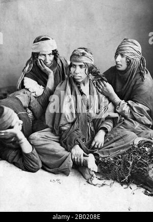 Syria: Bedouin women of the Syrian Desert. Photo by Tancrède R. Dumas (1830-1905), 1889.  Bedouin are a part of a predominantly desert-dwelling Arabian ethnic group traditionally divided into tribes, or clans, known in Arabic as ʿašāʾir. The term 'Bedouin' derives from a plural form of the Arabic word badawī, as it is pronounced in colloquial dialects. The Arabic term badawī derives from the word bādiyah, which means semiarid desert (as opposed to ṣaḥarāʾ which means desert).  Starting in the late nineteenth century, many Bedouin under British rule began to transit to a seminomadic life. Stock Photo