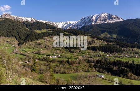 Small village of Yavuzkoy in a green valley with trees and with lots of small houses, mountains and snow in Turkey. Stock Photo