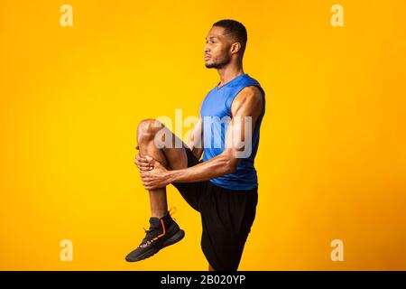 Young afro sportsman walks highly holding knee Stock Photo