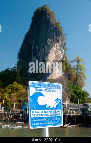 Thailand: Tsunami hazard zone sign, Panyi Muslim Fishing Village, Ao Phang Nga (Phangnga Bay) National Park, Phang Nga Province.  Ko Panyi is a massive karst outcrop in the lee of which a prosperous Thai Muslim fishing village shelters from the South-West Monsoon. The unusual location of the stilted Muslim fishing village, together with the unexpected mosque and minaret, has provided the inhabitants of Ko Panyi with an unexpected and welcome additional source of income in the years since the advent of tourism. Stock Photo