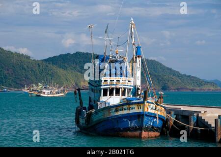 Thailand: Fishing boat at the pier, Bang Bao fishing village, Ko Chang, Trat Province.  In a country blessed with a plethora of beautiful islands, Ko Chang stands out as one of the loveliest. It’s also Thailand’s second largest island (after Phuket), but what makes it so appealing is its rugged aspect, and the way it rises suddenly from the sea, the usual lovely white sand Thai beaches, but backed by a solid hilly interior covered in wild jungle that seems to shelter the coast from the sea.  People visit Ko Chang for these pristine beaches. Stock Photo