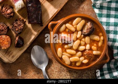 Typical Spanish fabada asturiana in crockpot on wooden table Stock Photo