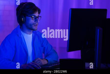 Programmer In Eyeglasses Coding On PC At Home, Low Light Stock Photo