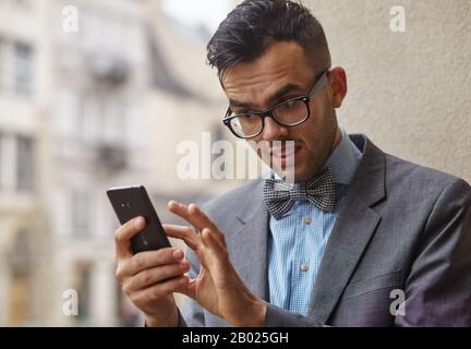 stylish man looking for something in his smartphone. he is concerned about what he has seen Stock Photo