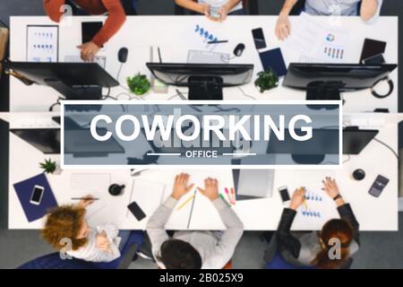 Coworking lettering over top view of working team Stock Photo