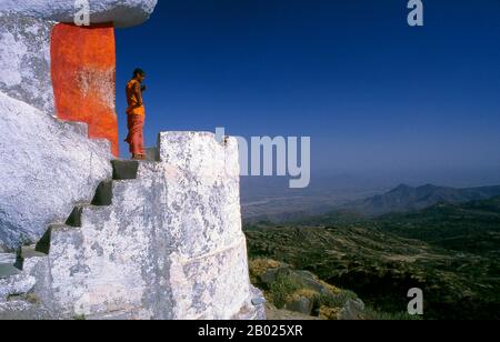 A swami (Sanskrit: स्वामी Svāmi [sʋáːmi]) is an ascetic or yogi who has been initiated into the religious monastic order founded by Adi Shankara, or to a religious teacher.  Mount Abu is a popular hill station in the Aravalli Range in Sirohi district of Rajasthan state in western India near the border with Gujarat. The mountain forms a distinct rocky plateau 22 km long by 9 km wide. The highest peak on the mountain is Guru Shikhar at 1,722 m (5,650 ft) above sea level. It is referred to as 'an oasis in the desert' as its heights are home to rivers, lakes, waterfalls and evergreen forests. Stock Photo