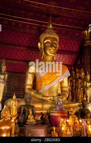 Wat Mai Suwannaphumaham dates from the early 19th century. The temple was once the residence of the Sangkhalat, the supreme patriarch of Buddhism in Laos.  The sim (ordination hall) is wooden, with a five-tiered roof in classic Luang Prabang style. The main attraction of the sim is the gilded walls of the front veranda, the designs of which recount scenes from the Ramayana and the Buddha’s penultimate incarnation (Vessantara Jataka).  For the first half of the 20th century the Phra Bang (Royal Buddha image in the Dispelling Fear mudra) was housed inside the sim, and it is still put on display Stock Photo