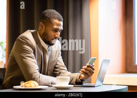 Portrait of afro guy using cellphone and computer Stock Photo