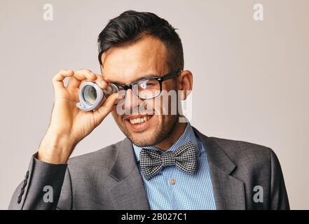 a stylish young businessman looking through a tube of dollar bills Stock Photo