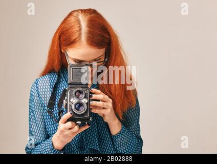 red-haired woman taking pictures using a classic camera Stock Photo
