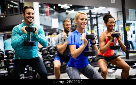 Group of young happy fit people doing exercises in gym Stock Photo
