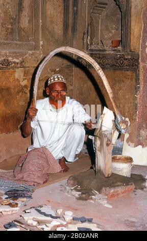 India: A marble craftsman at the tomb of I'timad-ud-Daulah, Agra.Etimad-ud-Daula's Tomb is a Mughal mausoleum in the city of Agra in the Indian state of Uttar Pradesh.  Along with the main building, the structure consists of outbuildings and gardens. The tomb, built between 1622 and 1628 represents a transition between the first phase of monumental Mughal architecture - primarily built from red sandstone with marble decorations, as in Humayun's Tomb in Delhi and Akbar's tomb in Sikandra - to its second phase, based on white marble and pietra dura inlay, elegantly realized in the Taj Mahal. Stock Photo