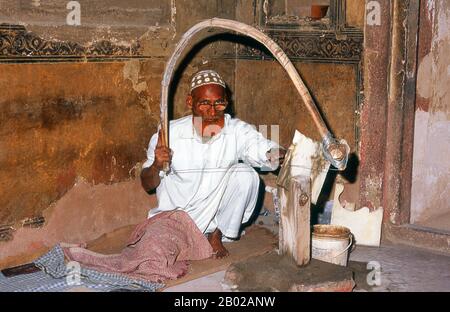 India: A marble craftsman at the tomb of I'timad-ud-Daulah, Agra.Etimad-ud-Daula's Tomb is a Mughal mausoleum in the city of Agra in the Indian state of Uttar Pradesh.  Along with the main building, the structure consists of outbuildings and gardens. The tomb, built between 1622 and 1628 represents a transition between the first phase of monumental Mughal architecture - primarily built from red sandstone with marble decorations, as in Humayun's Tomb in Delhi and Akbar's tomb in Sikandra - to its second phase, based on white marble and pietra dura inlay, elegantly realized in the Taj Mahal. Stock Photo