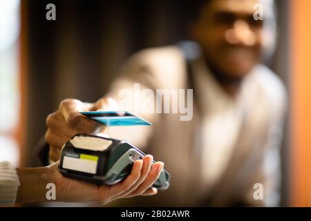 Afro businessman using modern contactless system at bar Stock Photo