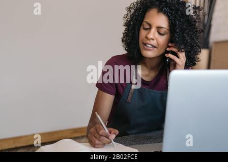 Entrepreneur talking on the phone while working in her studio Stock Photo