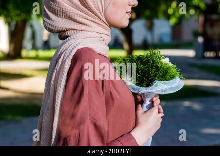 Woman in hijab graceful holding bouquet of green flowers Stock Photo