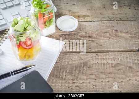 Healthy take-awayOffice lunch. Vegan vegetable salad in glass jars, with sliced fresh vegetables. Detox, raw eating and zero waste lunch concept. Stock Photo