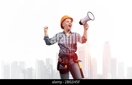 Expressive woman in helmet shouting into megaphone Stock Photo