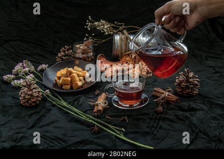 Bael fruit tea  is poured from a kettle into glass cup with bark of bael fruit, brown cane sugar cube Crispy butter toast. The properties of hot bael Stock Photo