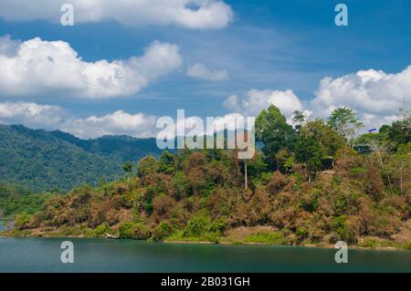 Cheow Lan Lake was created by the construction of  Rajjabrapha Dam in 1982, and is also known as Rajjabrapha Lake. Karst outcrops isolated from the mainland by the flooding rise from the waters of the lake to almost 1,000 m (3,000 feet) in height – that is, about three times the height of similar karst outcrops at Phang Nga Bay. Gibbons and eagles have access to these isolated peaks, but they are inaccessible to all but the most intrepid of climbers and provide a wonderful haven for rare wildlife.  Khao Sok National Park forms the largest and most dramatic tract of virgin forest in southern Th Stock Photo