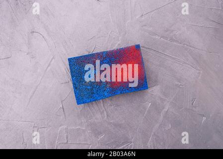 Red sponge to create texture in blue paint. Soft tool for decoration on a silver background Stock Photo