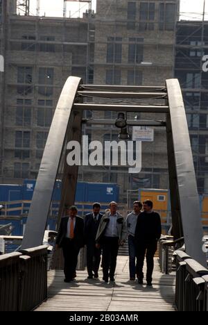 Office workers crossing a footbridge in the old warehouse area of modern offices and apartments in the Hamburg Port of Hamburg in Germany. Stock Photo