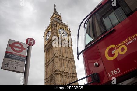 Big Ben, London. Abstract low angle view of the iconic landmark framed between a traditional red bus and bus stop in Westminster. Stock Photo